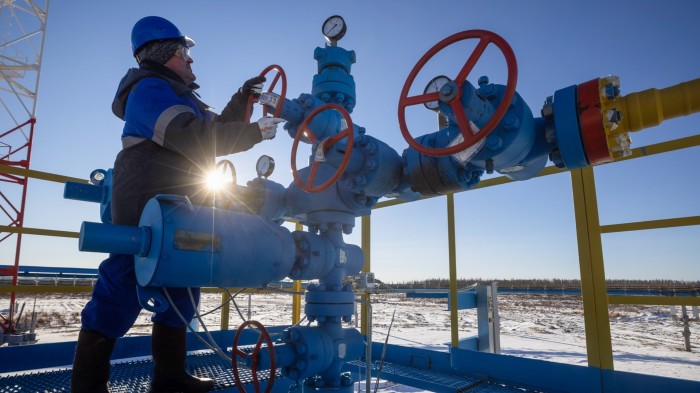 Worker turns a valve wheel at a gas well in Russia