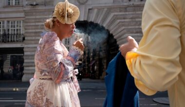 A woman lights a cigarette while walking down Regent Street in London