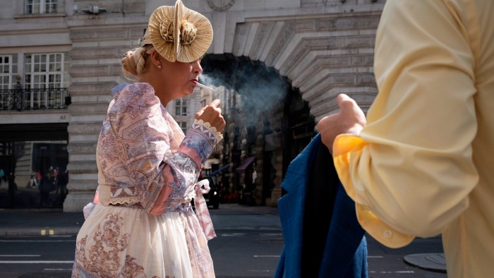 A woman lights a cigarette while walking down Regent Street in London