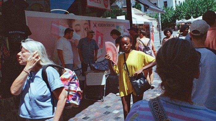 A woman uses a fan to cool herself near Monastiraki Square in Athens, Greece