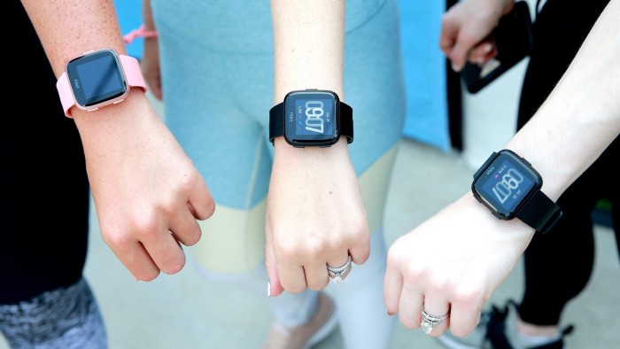People display their Fitbit watches during a workout