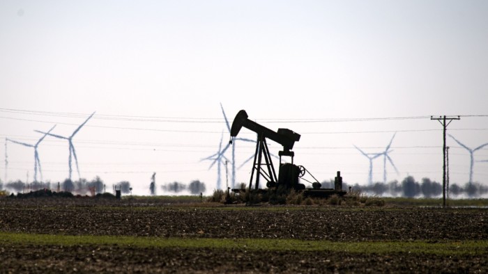 A pump jack and wind turbines in a field in Corpus Christi, Texas