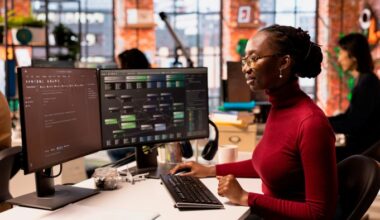 Woman working on software development at a dual-screen workstation in a collaborative office space