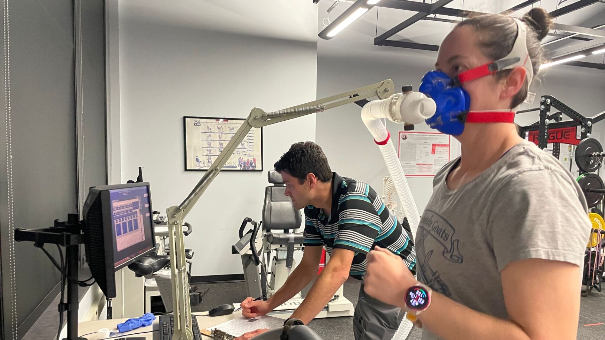 Beth on the treadmill with a mask, Dr. Wisniewski in the background
