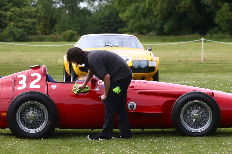 A person cleaning a red vintage race car.