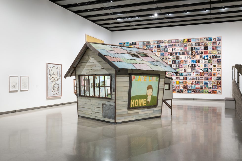A structured art installation resembling a house in an exhibition space