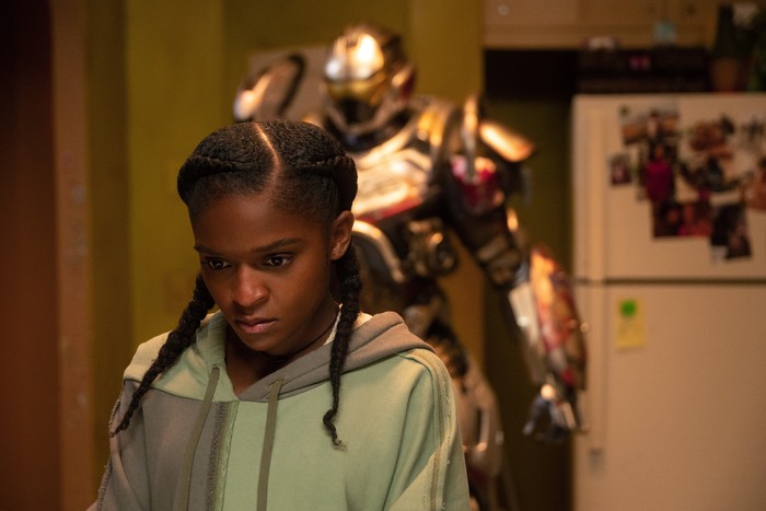 Dominique Thorne plays Riri Williams in Ironheart, staring intensely with her armoured suit behind her