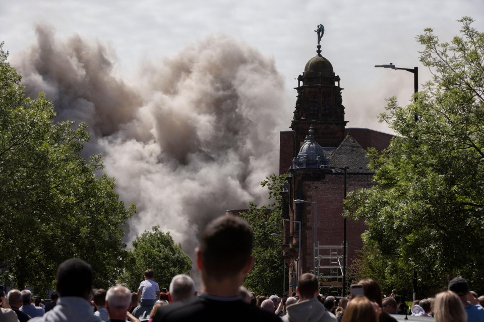 Controlled demolition of tower blocks in Glasgow, Scotland, viewed from behind a crowd of onlookers.