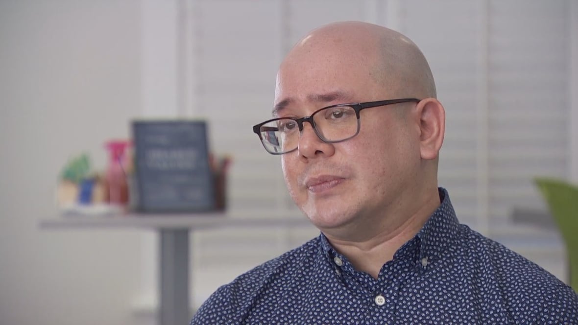 A bald man with glasses looks solemn.