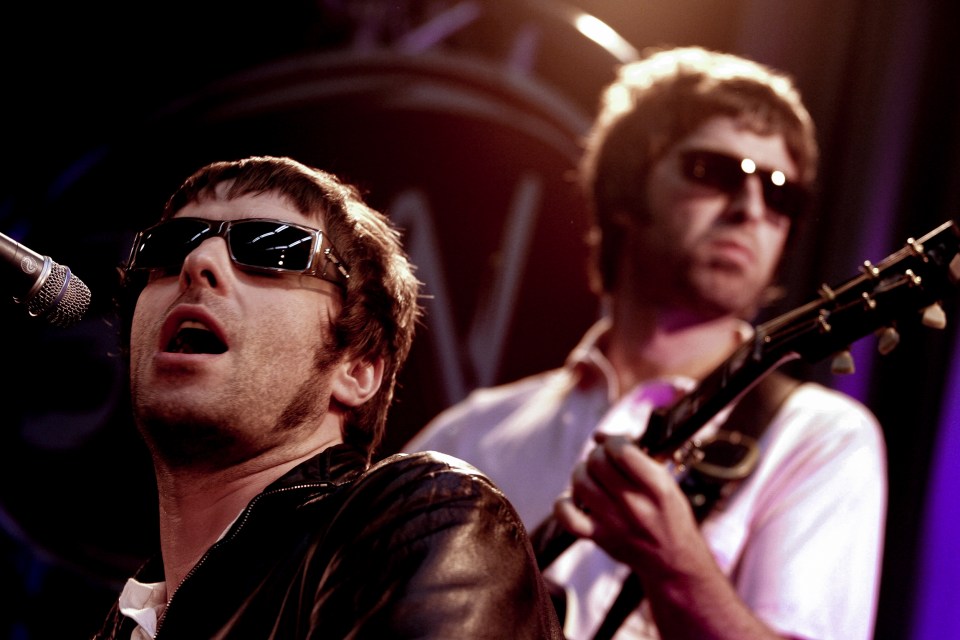 Liam and Noel Gallagher of Oasis performing on stage.