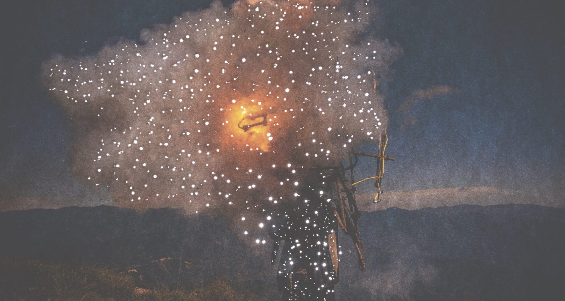 small holes pierce a dark photo of a person holding fire