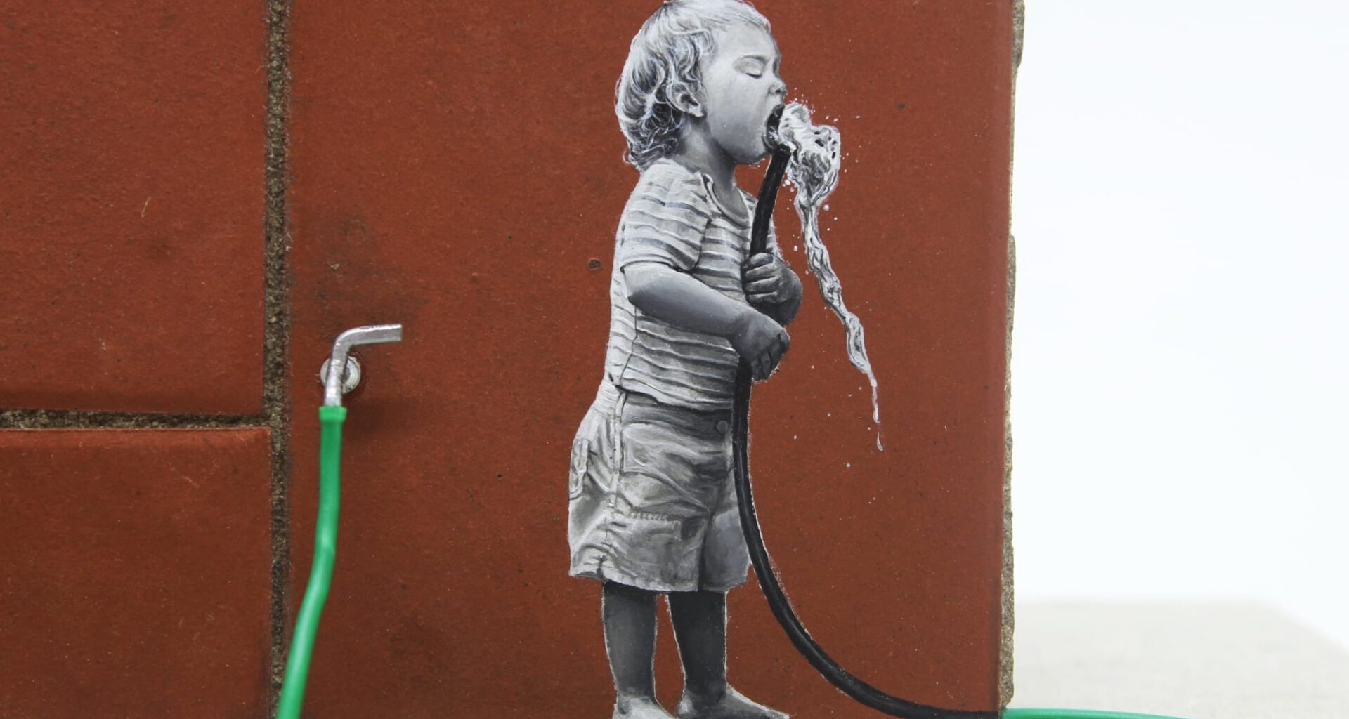 a detail of a child drinking from a green hose