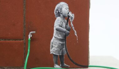 a detail of a child drinking from a green hose