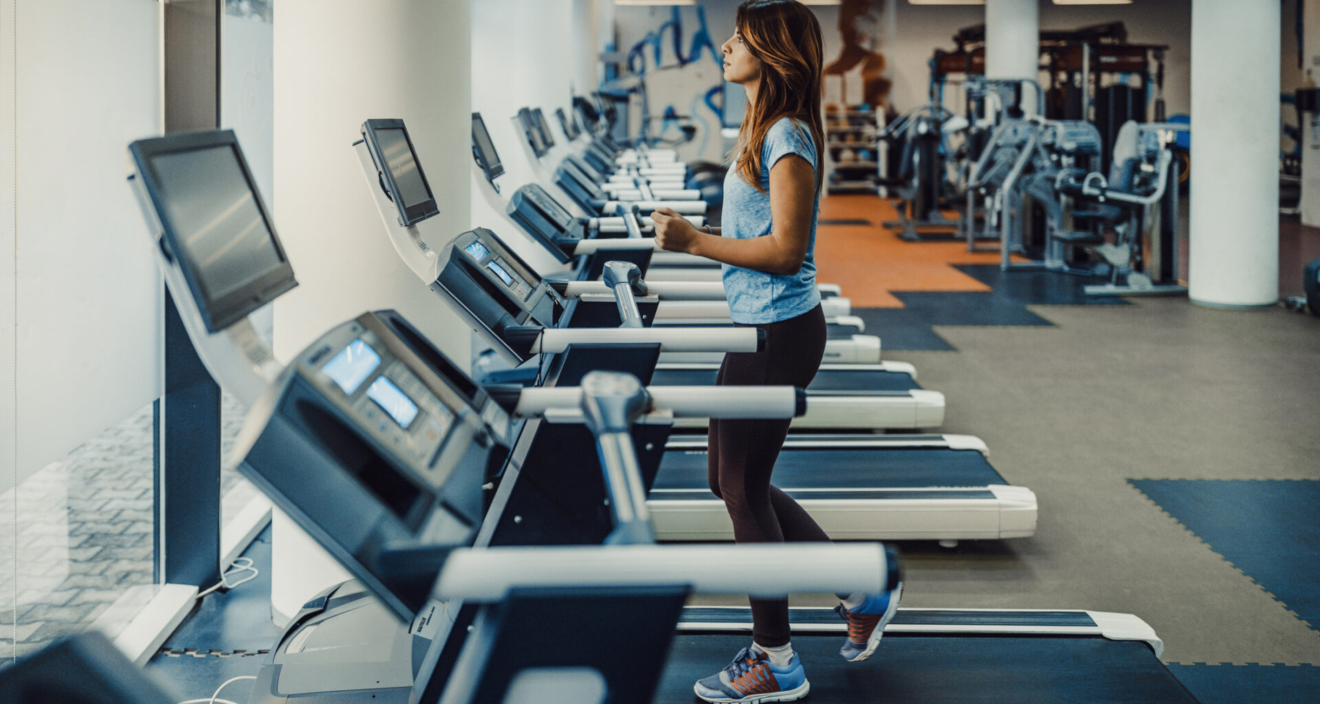 Woman walking on treadmill in empty gym