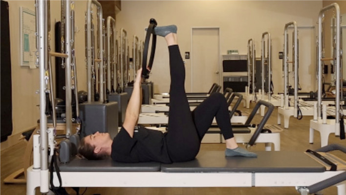 Woman on a Reformer Pilates machine demonstrating an exercise