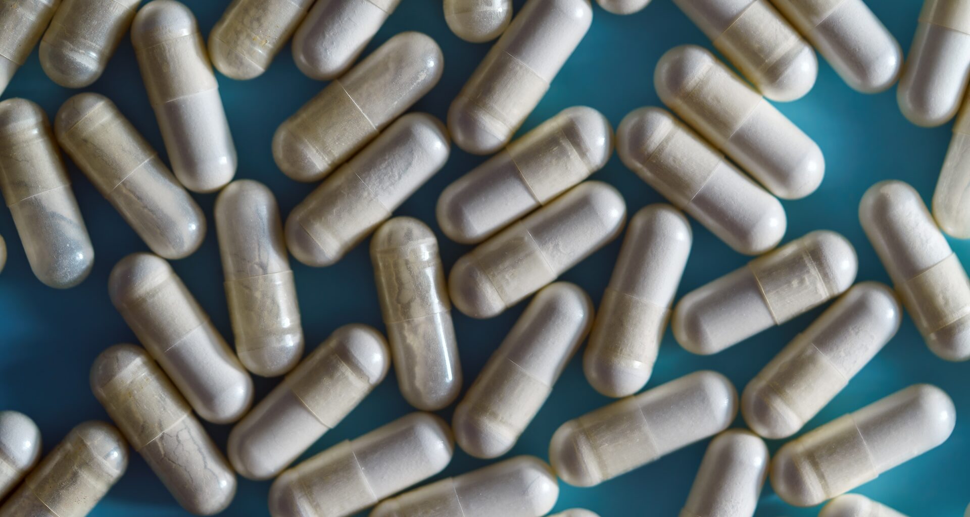 many supplement capsules scattered on a blue background