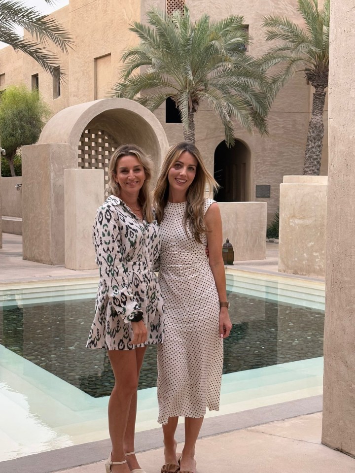 Two women posing for a photo by a pool.