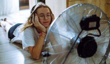 Teenage girl wearing headphones lying on the floor in front of a fan