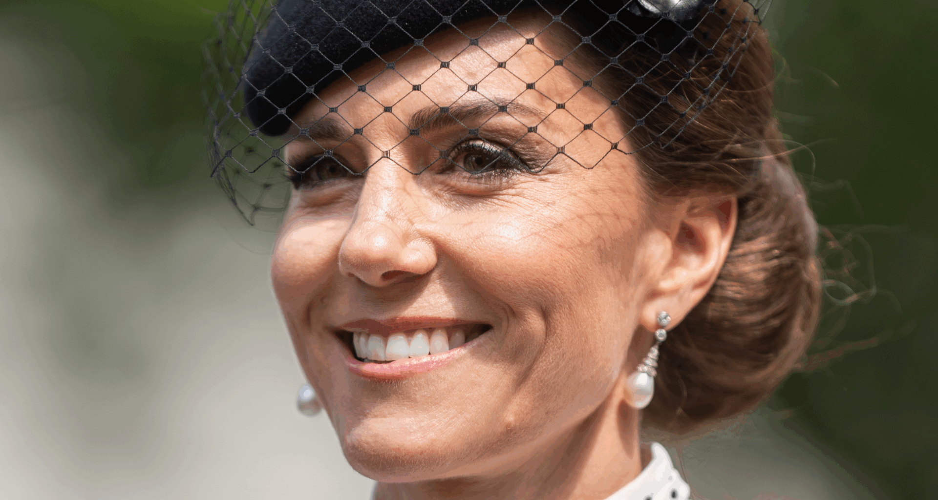 Kate Middleton wearing a white polka dot dress and black hat with a veil