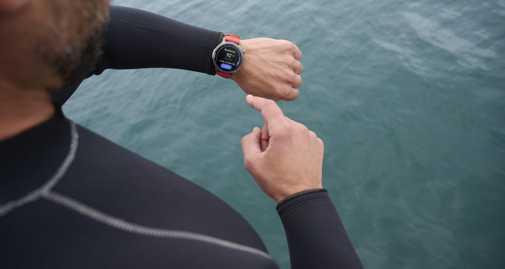 A man in a wetstuit looks at his Amazfit Balance 2 smartwatch