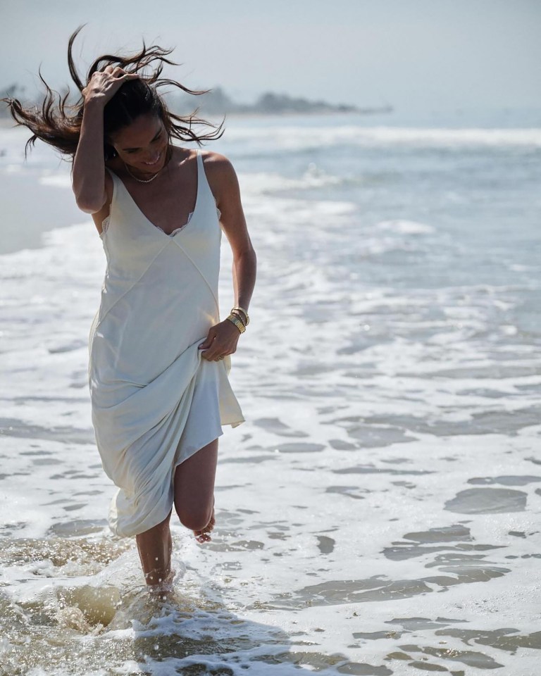 Woman in white dress running in ocean waves.