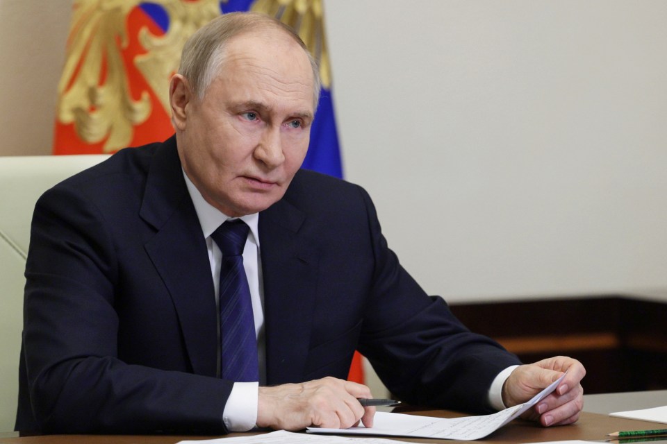 Vladimir Putin reviewing documents at a meeting.