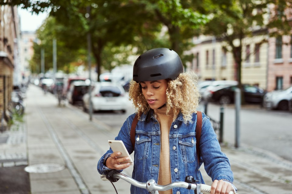 Woman on a bicycle checking her phone.