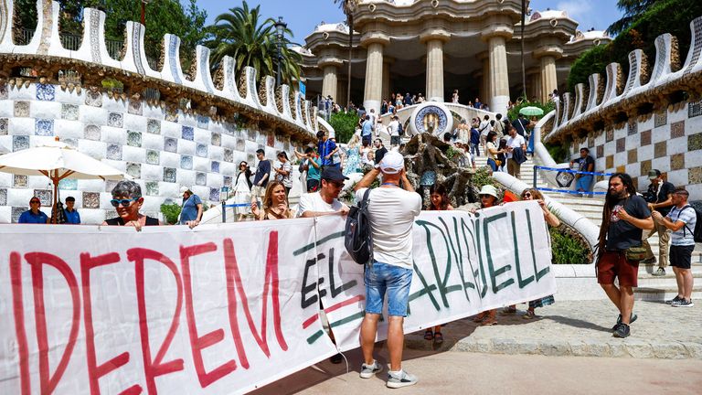 A tourist refuses to move for demonstrators holding a banner which reads "recover Park Guell" in Barcelona. Pic: Reuters