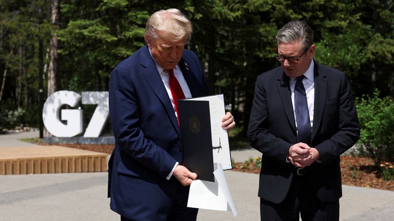 U.S. President Donald Trump holds a signed U.K.-U.S. trade agreement during a meeting with Britain's Prime Minister Keir Starmer, at the G7 summit, in Kananaskis, Alberta, Monday, June 16, 2025. (Suzanne Plunkett/Pool Photo via AP)