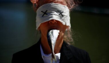 A protester with a mackerel in her mouth takes part in a protest outside the U.N. Ocean Conference to demand member states to finalise a tre