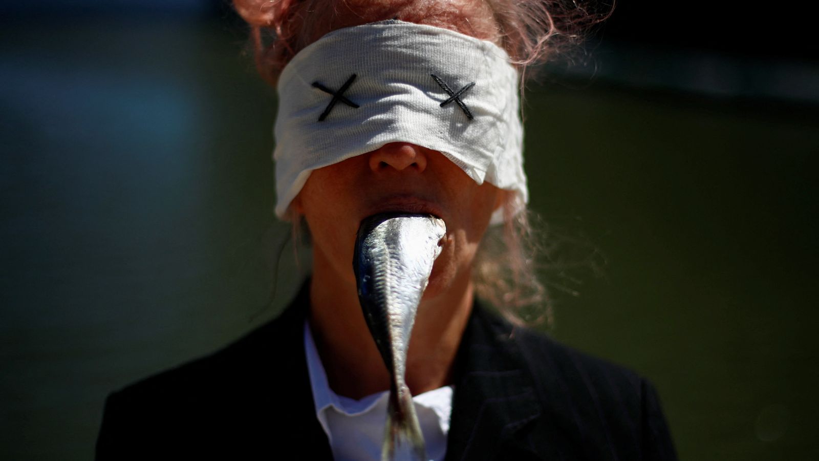 A protester with a mackerel in her mouth takes part in a protest outside the U.N. Ocean Conference to demand member states to finalise a tre