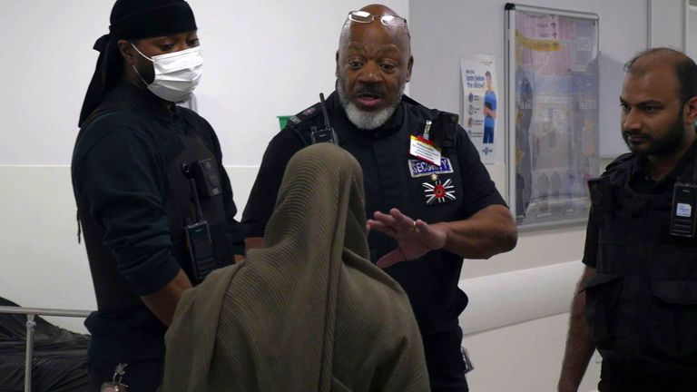 Security guards speak to a woman