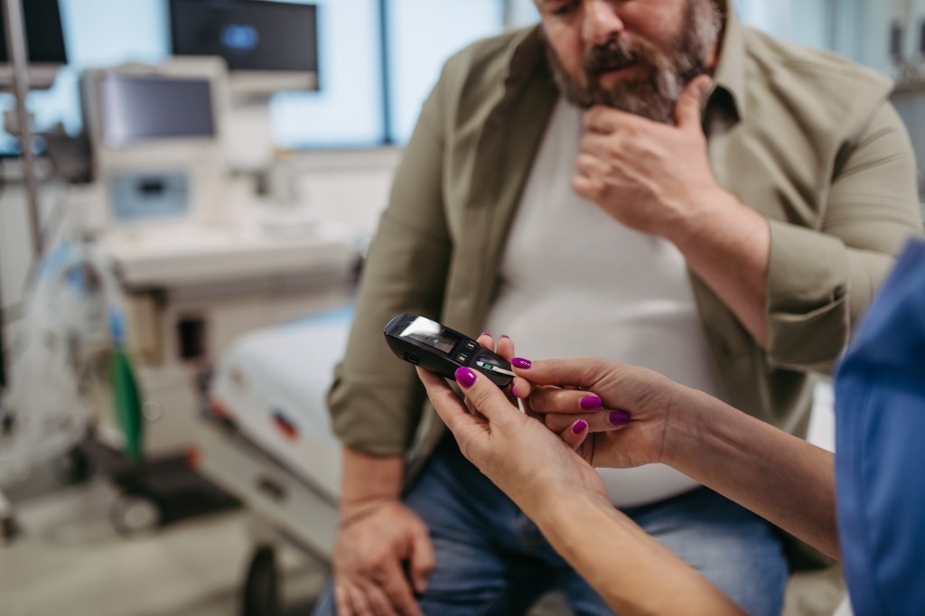 Doctor checking a patient's blood glucose level with a glucometer.