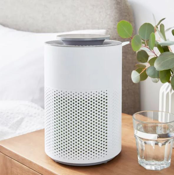 White air purifier on a nightstand.