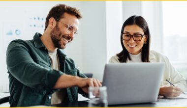 Man and woman working on a laptop computer, smiling.