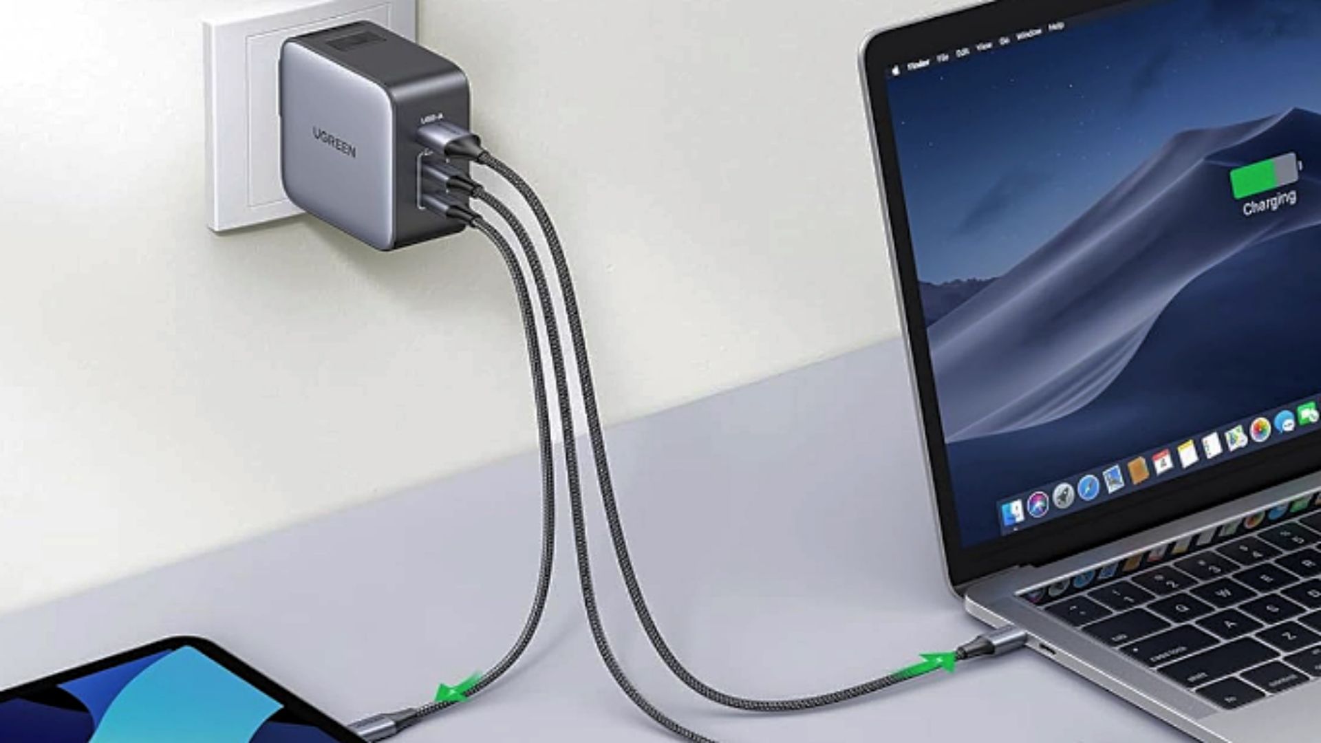 A UGREEN Nexode 65W Travel Charger plugged into a wall outlet and charging several devices.