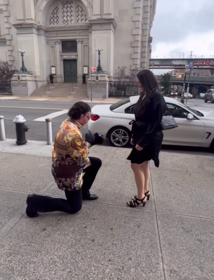 Man proposing to a woman on a city street.
