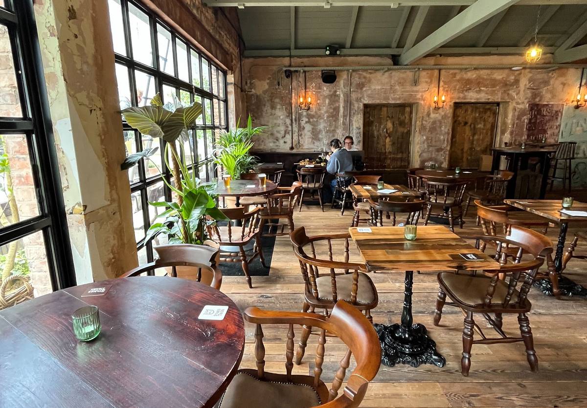 wooden chairs and tables inside stables tavern pub in manchester
