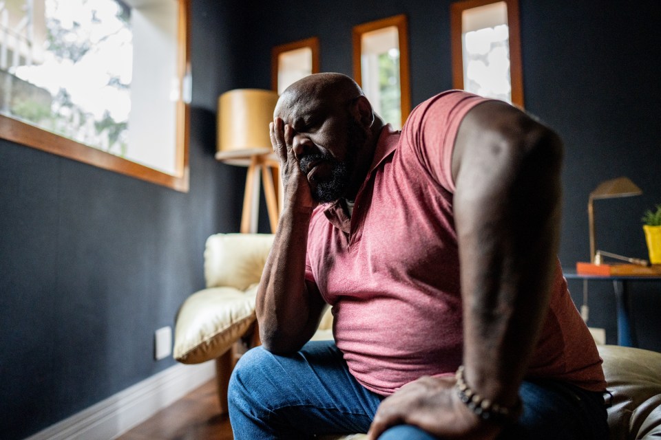 A worried mature man sitting at home, head in hands.