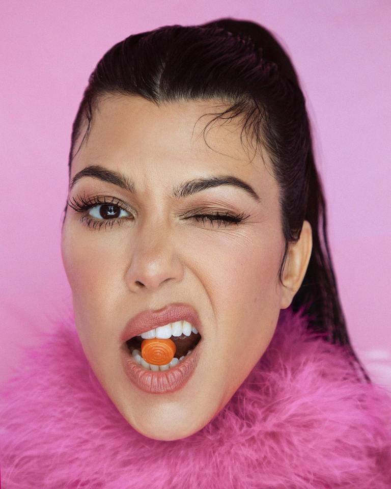 Kourtney Kardashian in a Lemme ad, winking and holding a vitamin in her mouth.