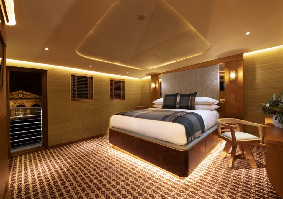 Hotel room with a large bed and a view of a city at night.