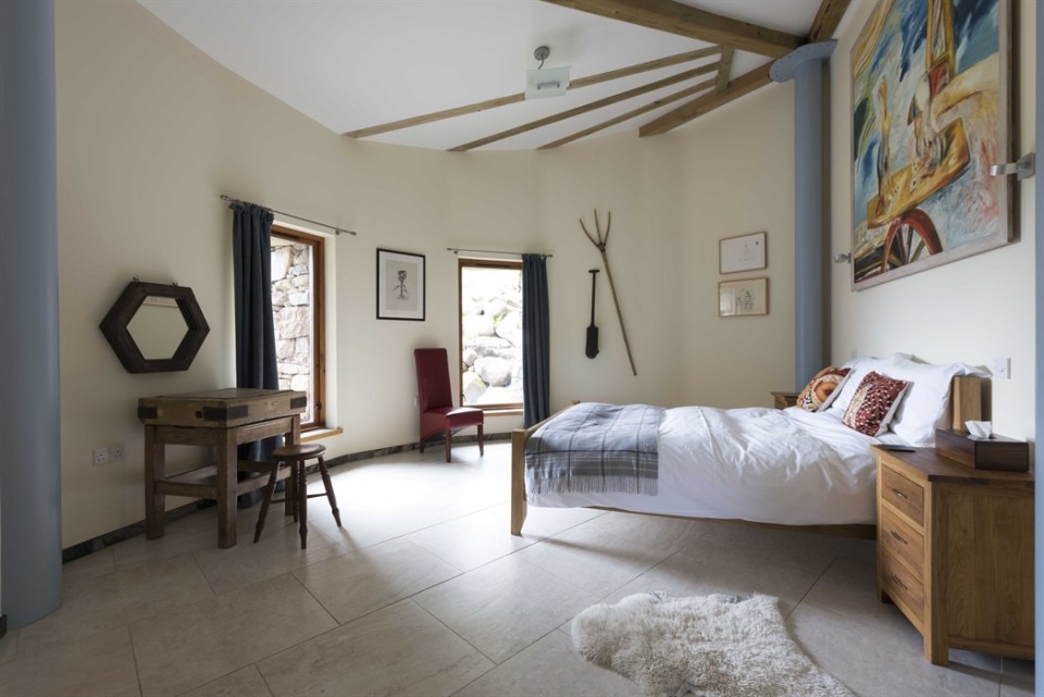 Bedroom with a large bed, wooden furniture, and artwork.