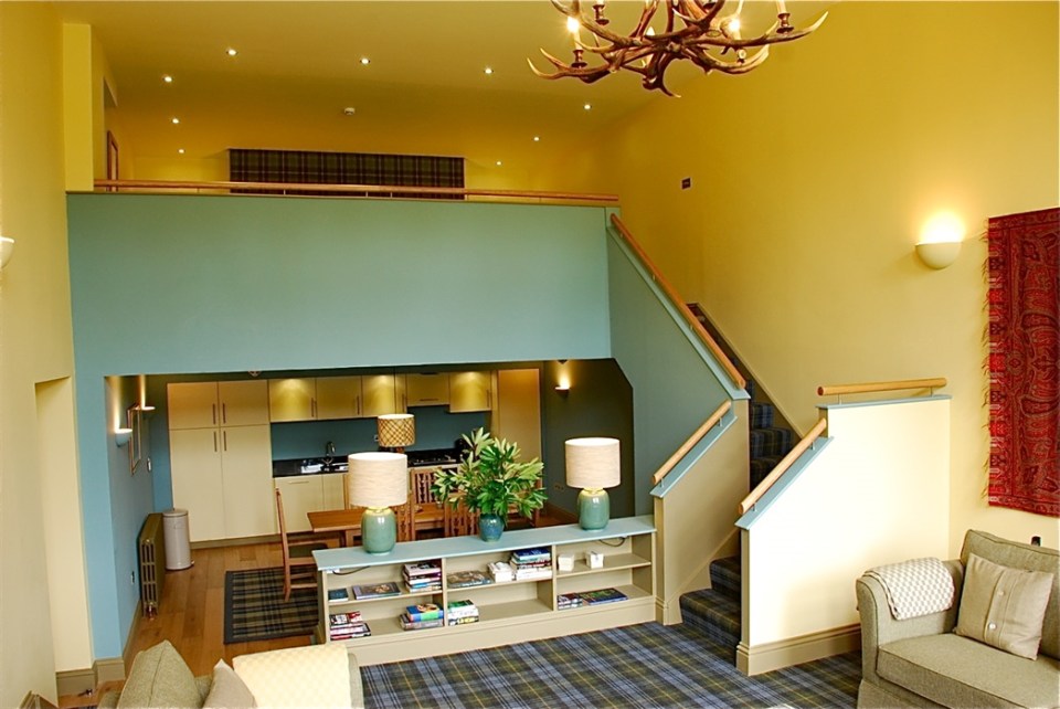 Interior view of a loft apartment with a kitchen, living area, and stairs.