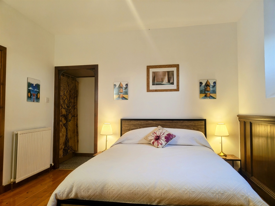 Bedroom with a bed, nightstands, and artwork.