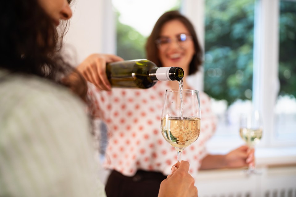 Woman pouring white wine for her friend.