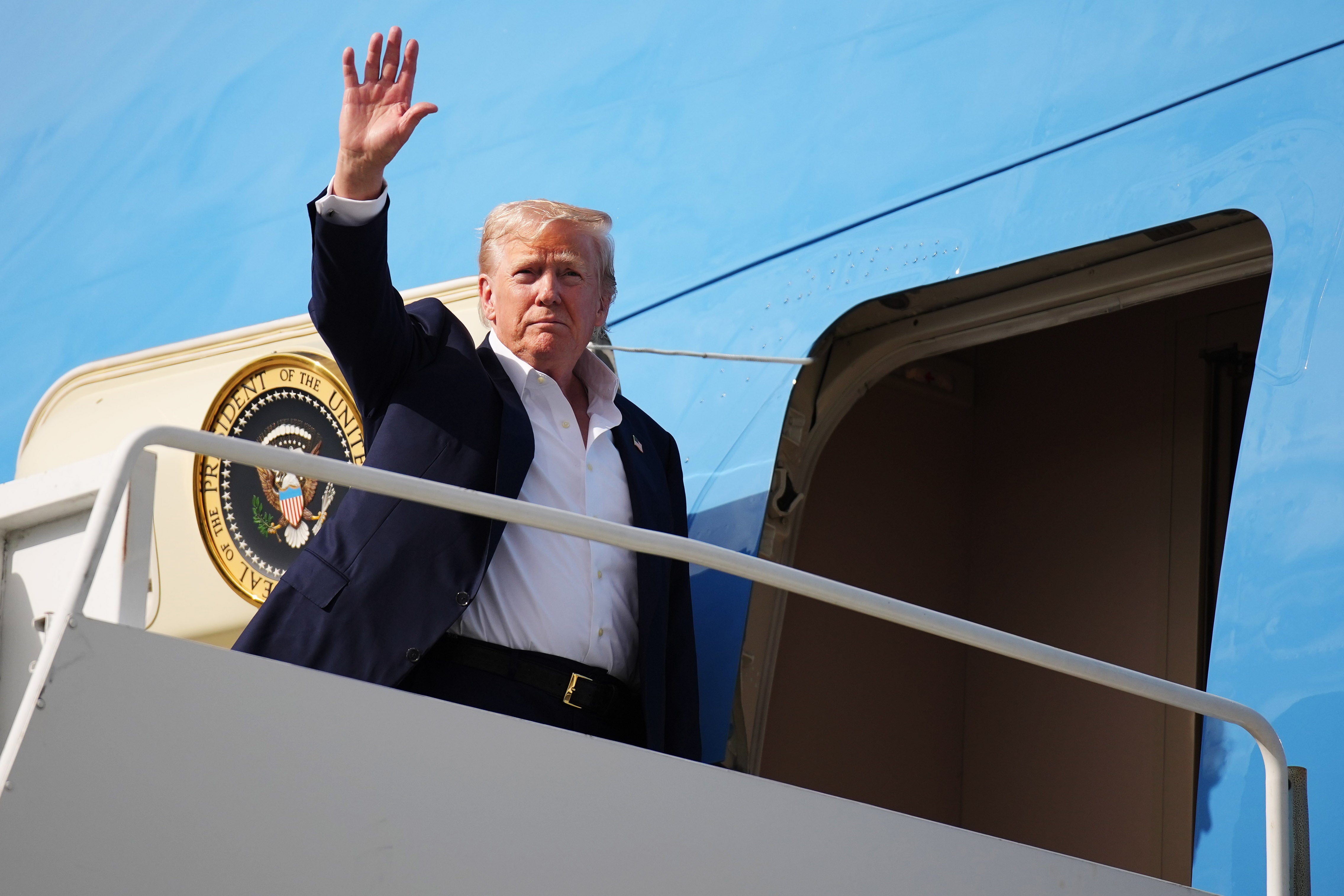 US president Donald Trump waves as he boards Air Force One at RAF Lossiemouth in Scotland