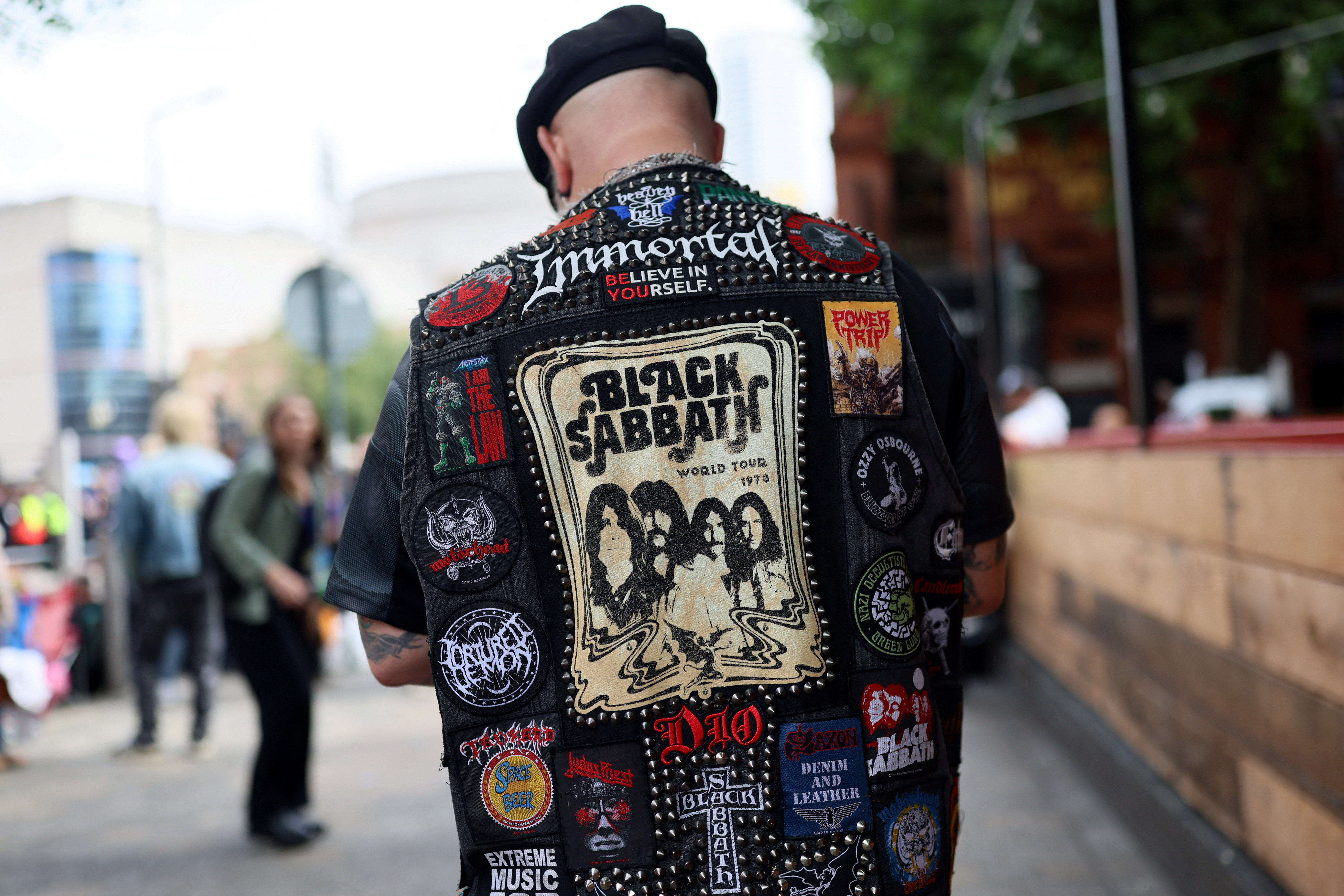 Man wearing a studded vest with Black Sabbath patches.