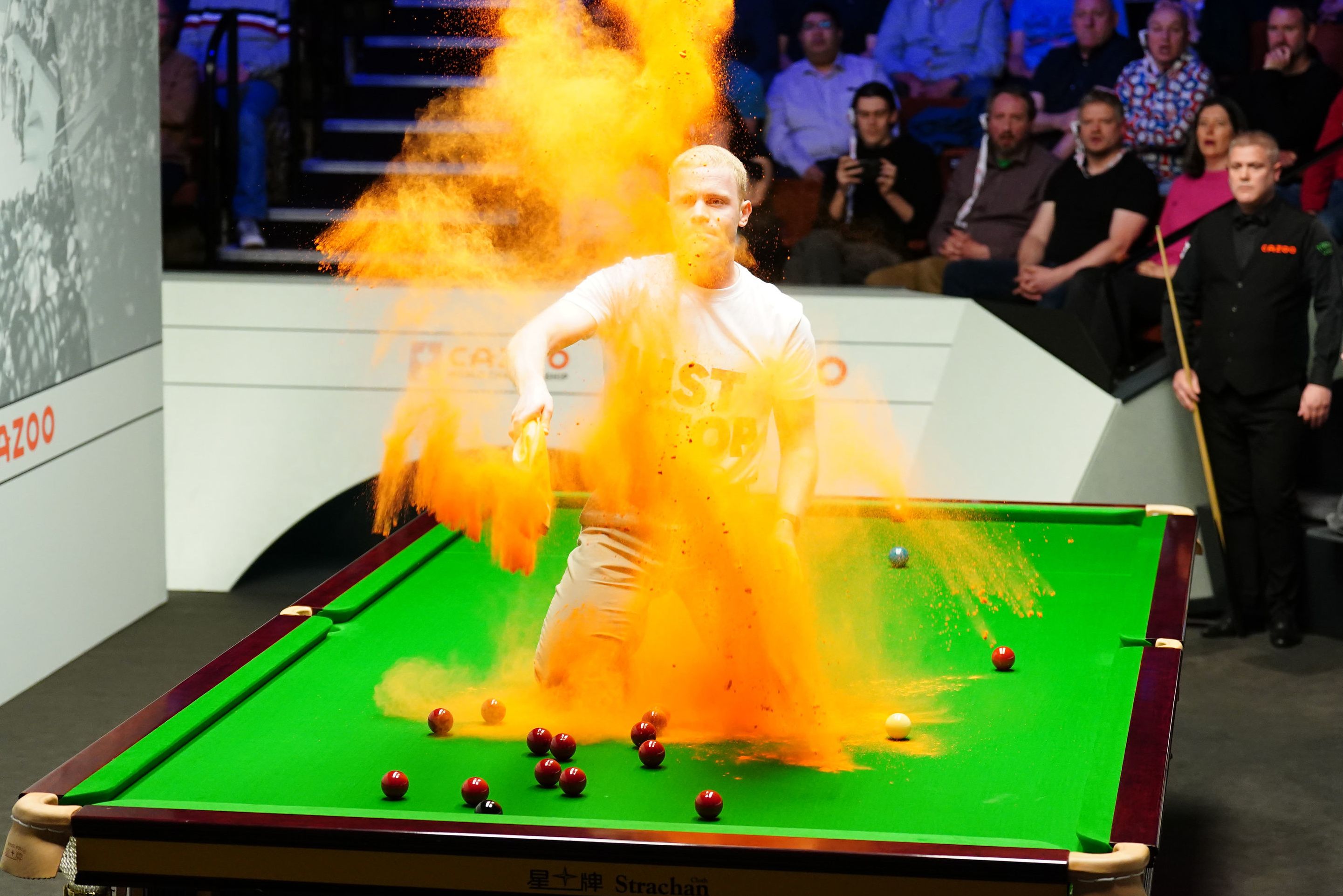 A protester throws orange powder onto a snooker table during a match.