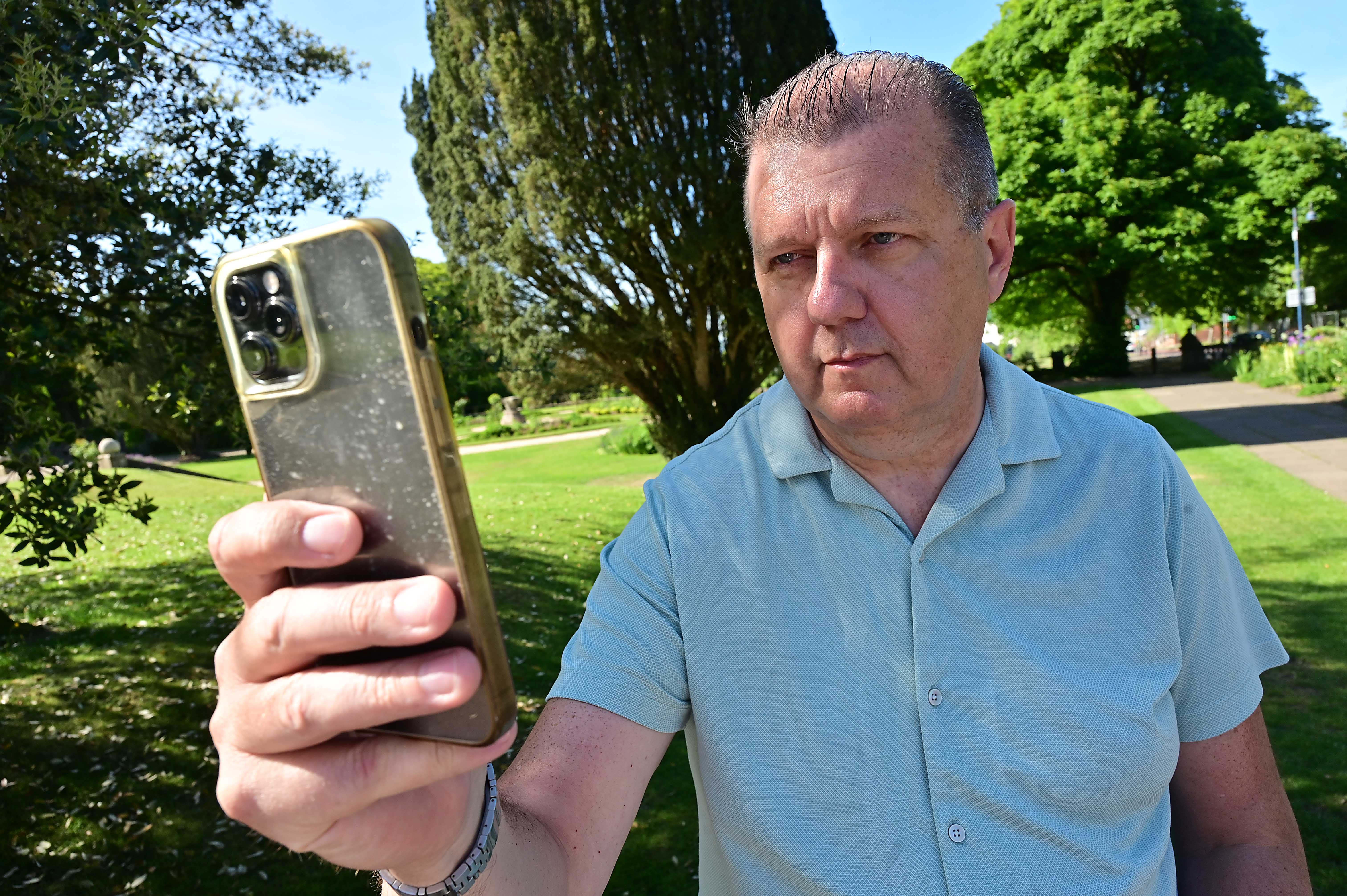 Man in a park using a safety app on his phone.
