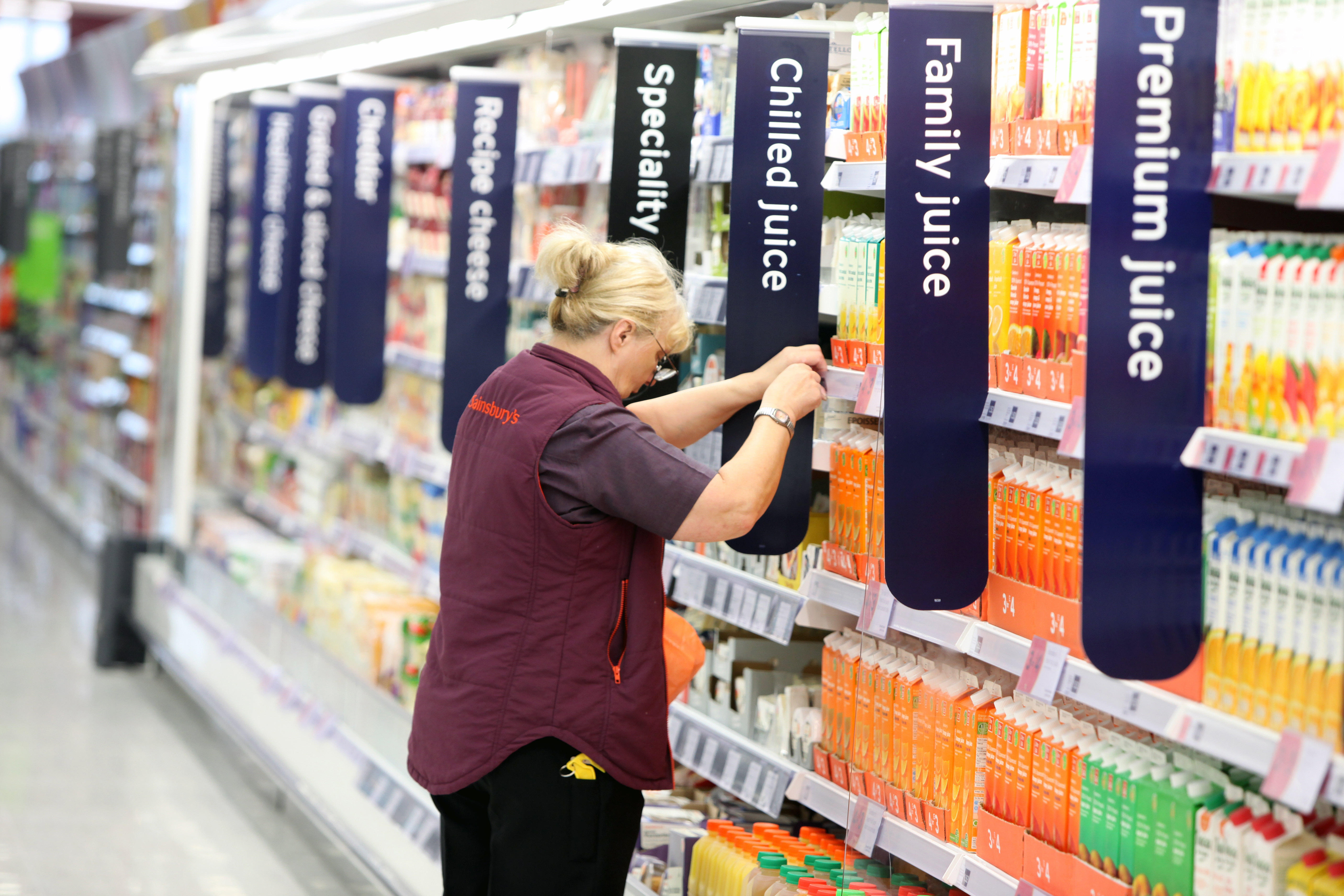 Sainsbury's employee stocking juice shelves.